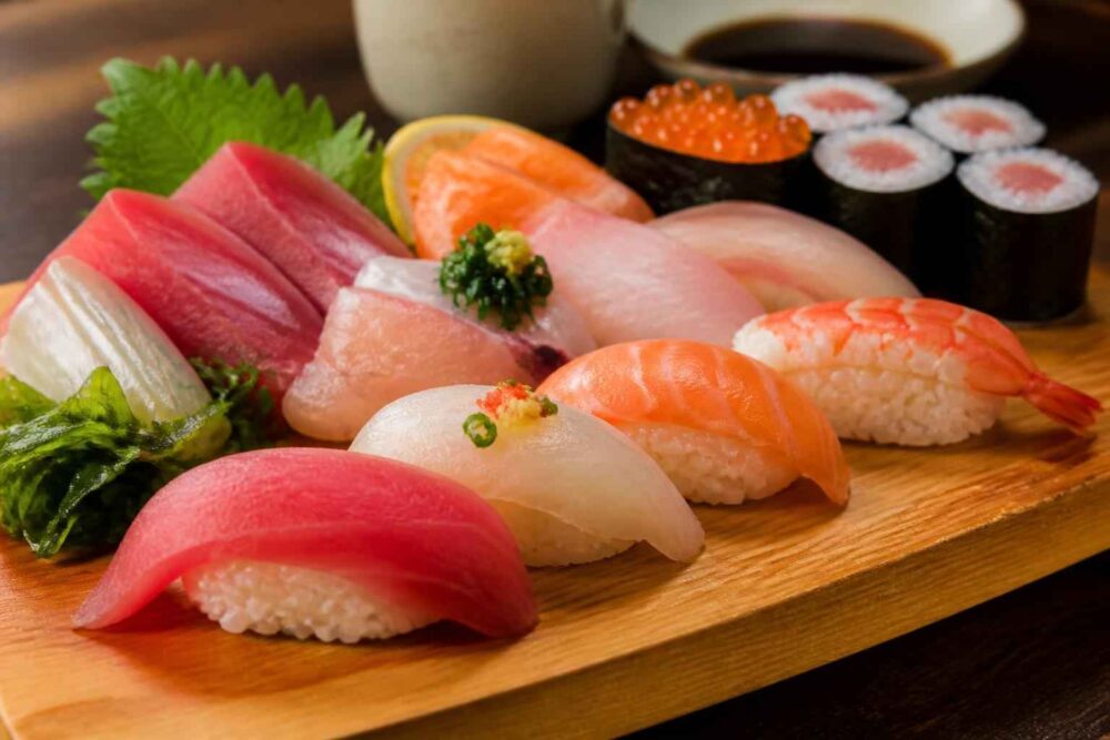 Różnorodne sushi, w tym nigiri i maki, podane na drewnianej desce z sosem sojowym