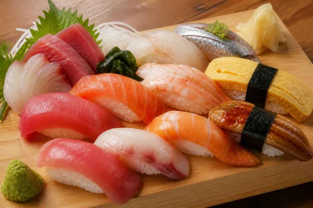 Różnorodne nigiri z tuńczykiem, łososiem, krewetką, rybą i omletem tamago na desceasynda
