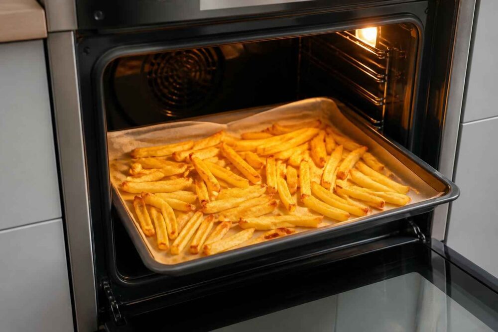 Blacha z chrupiącymi frytkami pieczonymi w rozgrzanym piekarniku